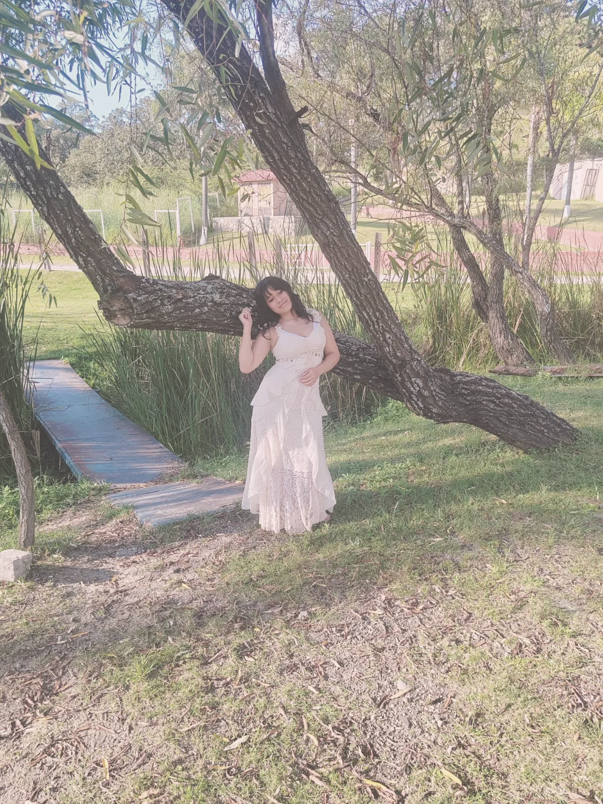 María Andrea de pie bajo un árbol inclinado